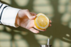 close up shot of a person holding a slice of a lemon